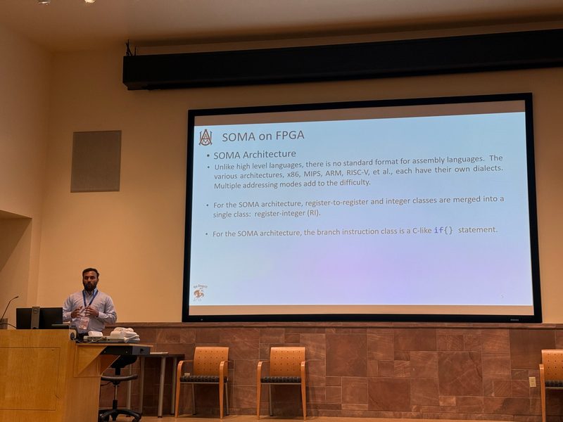 Sharoon presenting at a lectern beside a projected slide titled “SOMA on FPGA” with the Alabama A&M logo